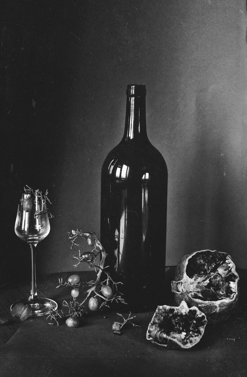 black wine bottle and wine glass beside fruits